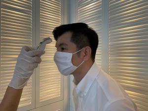 um homem usando uma máscara e luvas segurando um par de tesouras em K Maison Boutique Hotel em Bangkok