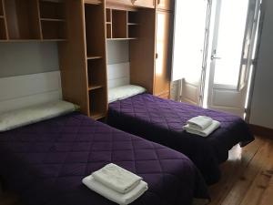 2 Betten in einem Zimmer mit lila Bettwäsche und Handtüchern in der Unterkunft PR Paz de Agra in Santiago de Compostela