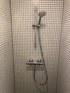 prysznic z głowicą prysznicową na ścianie wyłożonej kafelkami w obiekcie Rooms in quiet Yellow Courtyard Apartment w Kopenhadze