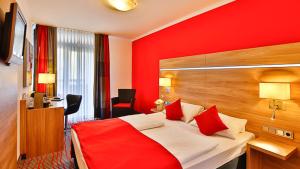 a red bedroom with a bed with red pillows at Hotel Wallis in Munich