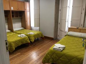 Zimmer mit 2 Betten, grünen Decken und Holzböden in der Unterkunft PR Paz de Agra in Santiago de Compostela