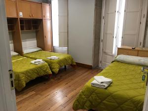 a room with two beds with green blankets and wooden floors at PR Paz de Agra in Santiago de Compostela