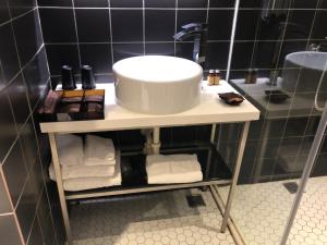 a bathroom with a sink and towels on a shelf at Hotel PaPa Whale in Taipei