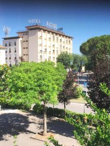 a large hotel with a tree in front of a building at Hotel Ristorante Alcide in Poggibonsi