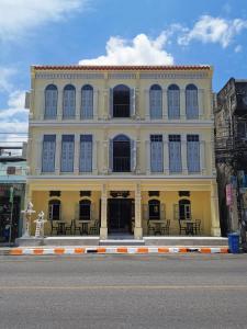 a yellow building with black windows on a street at Capzule Bed Phuket in Phuket