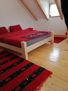 a bedroom with a bed with a red comforter and a rug at Balabani Local Stay in Podgorica