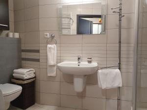 a white bathroom with a sink and a mirror at Apartament w Porcie - 365PAM in Kołobrzeg