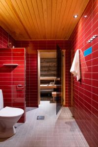 uma casa de banho vermelha com WC e azulejos vermelhos em Kakslauttanen Arctic Resort - Igloos and Chalets em Saariselka