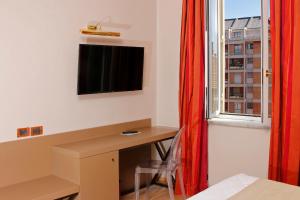 a room with a desk and a window with a television at Hotel Arcangelo in Rome