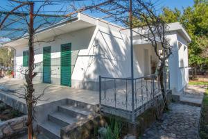 a white house with green shutters and stairs at Apartman Soto in Pirovac
