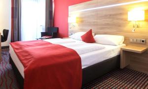 una camera d'albergo con un grande letto con una coperta rossa di Hotel Wallis by ANS a Monaco