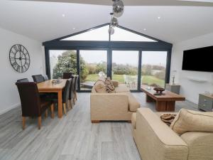 sala de estar con sofá y mesa con sillas en Lake View Cottage, en Rhosneigr