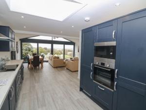 a kitchen with blue cabinets and a living room at Lake View Cottage in Rhosneigr