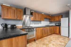 cocina con armarios de madera y nevera blanca en Granary Suite No22 - Donnini Apartments en Ayr