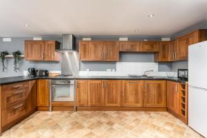 uma cozinha com armários de madeira e um frigorífico branco em Granary Suite No22 - Donnini Apartments em Ayr