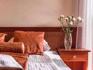 a vase of flowers sitting on a nightstand next to a bed at Villa Magnat SPA, JACUZZI, SAUNA, TĘŻNIA SOLANKOWA in Białka Tatrzańska