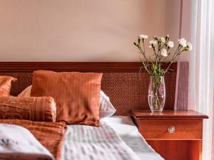 un jarrón de flores sentado en una mesita de noche junto a una cama en Villa Magnat SPA, JACUZZI, SAUNA, TĘŻNIA SOLANKOWA, en Białka Tatrzanska