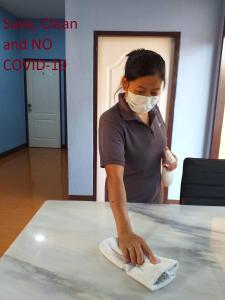 a woman in a mask wiping a table with a towel at Home of River Kwai in Kanchanaburi City