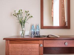 einen Holztisch mit einer Vase aus Blumen und einem Spiegel in der Unterkunft Villa Magnat SPA, JACUZZI, SAUNA, TĘŻNIA SOLANKOWA in Białka Tatrzańska