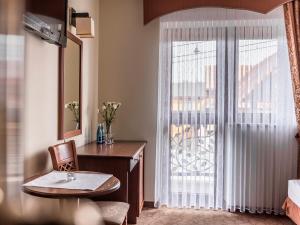 a hotel room with a desk and a window at Villa Magnat SPA, JACUZZI, SAUNA, TĘŻNIA SOLANKOWA in Białka Tatrzańska