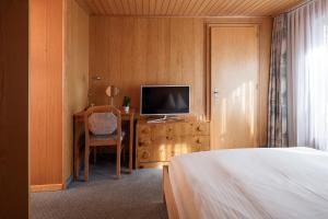 a bedroom with a bed and a desk with a television at Hotel Continental in Zermatt