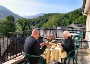 Ein Mann und eine Frau, die an einem Tisch auf einem Balkon sitzen in der Unterkunft Hôtel des Rosiers in Lourdes