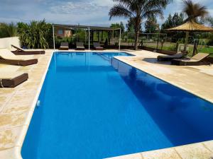 a large blue swimming pool with chairs and an umbrella at Cabañas Las Primorosas in Cañuelas
