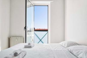um quarto com uma cama branca e toalhas em LUVI - Alzaia Naviglio Pavese em Milão