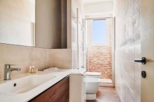 uma casa de banho com um lavatório, um WC e uma janela. em LUVI - Alzaia Naviglio Pavese em Milão
