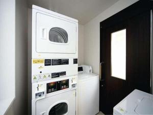 een keuken met een wasmachine en droger aan de muur bij Hotel Hillarys in Osaka
