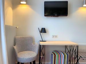 a room with a desk and a tv and a chair at Hôtel Edouard 6 by Malone in Paris