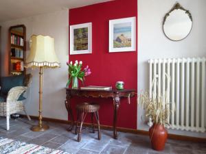 Zimmer mit einer roten Wand, einem Schreibtisch und einer Lampe in der Unterkunft Gästezimmer im Freudenthal in Extertal