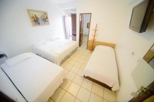 a white room with two beds and a television at Hotel Rio Pregui&ccedil;as in Barreirinhas