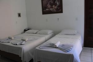 two beds with bow ties on them in a room at Hotel Rio Pregui&ccedil;as in Barreirinhas