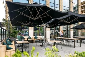 eine Terrasse mit Tischen und Stühlen und einem großen Sonnenschirm in der Unterkunft The Social Hub Eindhoven in Eindhoven