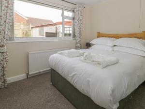 um quarto com uma grande cama branca e uma janela em Arbour Retreat em Filey