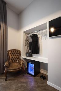 une pièce avec une chaise, une télévision et une étagère dans l'établissement Ara Suite, à Rome