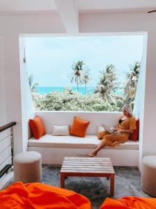 a woman sitting on a couch in front of a window at Bliss Dhigurah in Dhigurah