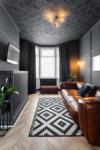 a living room with a leather couch and a rug at Air Host and Stay - Stanley House Large house, sleeps 10 5 mins to city centre in Liverpool