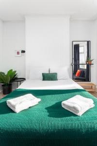 a white bed with green sheets and towels on it at Air Host and Stay - Stanley House Large house, sleeps 10 5 mins to city centre in Liverpool