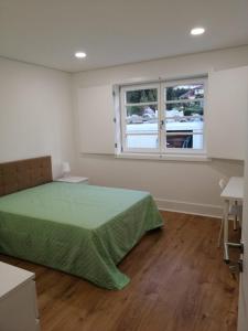 um quarto com uma cama verde e uma janela em 4-As moradias centro em Guimarães