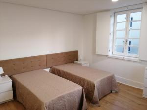 a bedroom with two beds and a window at 4-As moradias centro in Guimarães