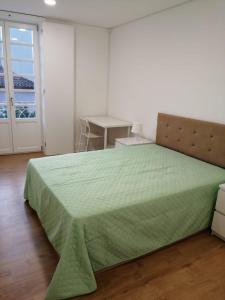 a bedroom with a green bed and a table at 4-As Moradias Centro in Guimarães
