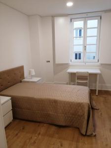um quarto com uma cama, uma secretária e uma janela em 4-As moradias centro em Guimarães
