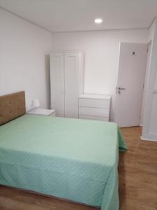 um quarto com uma cama com uma colcha verde em 4-As moradias centro em Guimarães