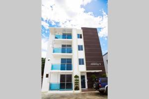 a white building with blue windows and a car parked in front at Modern 3 Bedroom Apt with Wifi and AC Near Airport and Major Areas in Santiago de los Caballeros