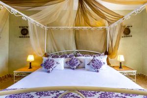 a bedroom with a canopy bed with purple and white pillows at Villa Thaifa & SPA in Marrakesh +175 photos