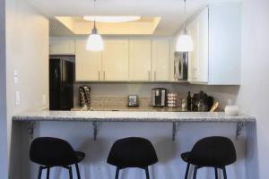 una cucina con armadi bianchi e sgabelli neri da bar di Free Parking - CHOC and St Joseph's Hospital Adjacent - 1 bedroom Apartment a Santa Ana