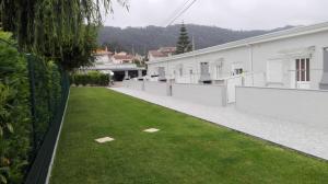 un patio con césped verde junto a edificios blancos en Maison de vacances et week-end, 2 en Esposende