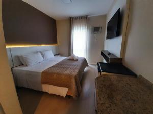 a hotel room with a bed and a television at Caravaggio Praia Hotel in Florianópolis +36 photos